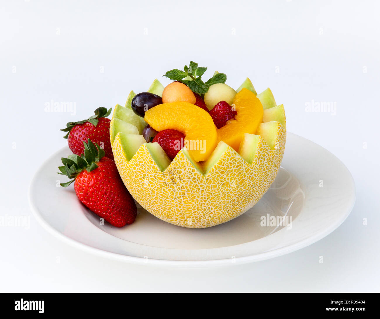 Fancy cut melon with assorted fruit inside isolated on a white background Stock Photo
