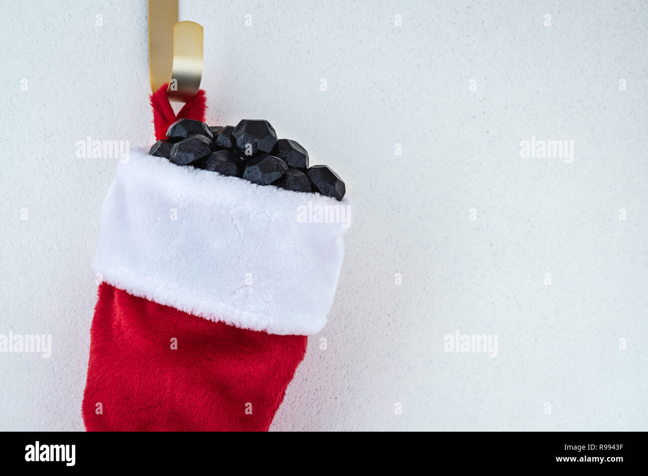 Close Up Of Traditional Red And White Plush Christmas Stocking Stuffed With Coal Shaped Candy On A Gold Hook Against A White Background Stock Photo Alamy