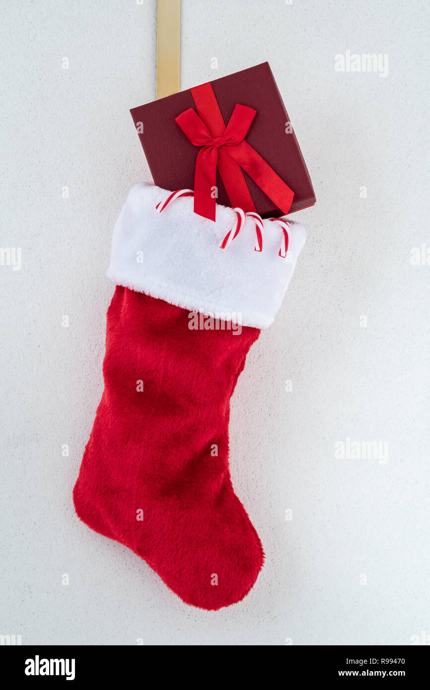 Traditional Red And White Plush Christmas Stocking With Candy Canes And A Red Wrapped Present On A Gold Hook Against A White Background With Silver F Stock Photo Alamy