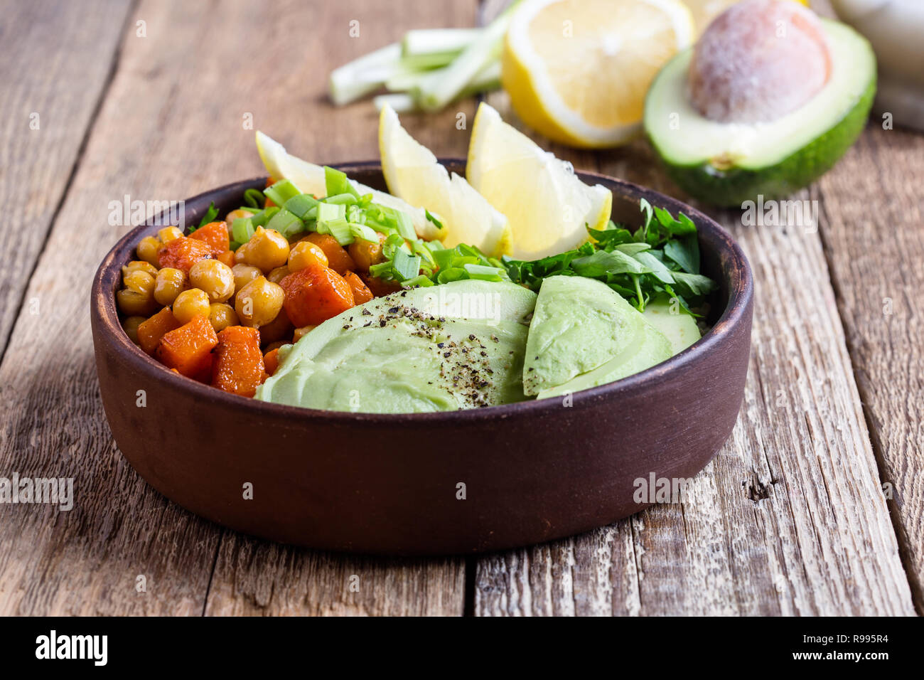 Healthy chickpea avocado quinoa bowl on rustic wooden table, plant based food, selective focus Stock Photo