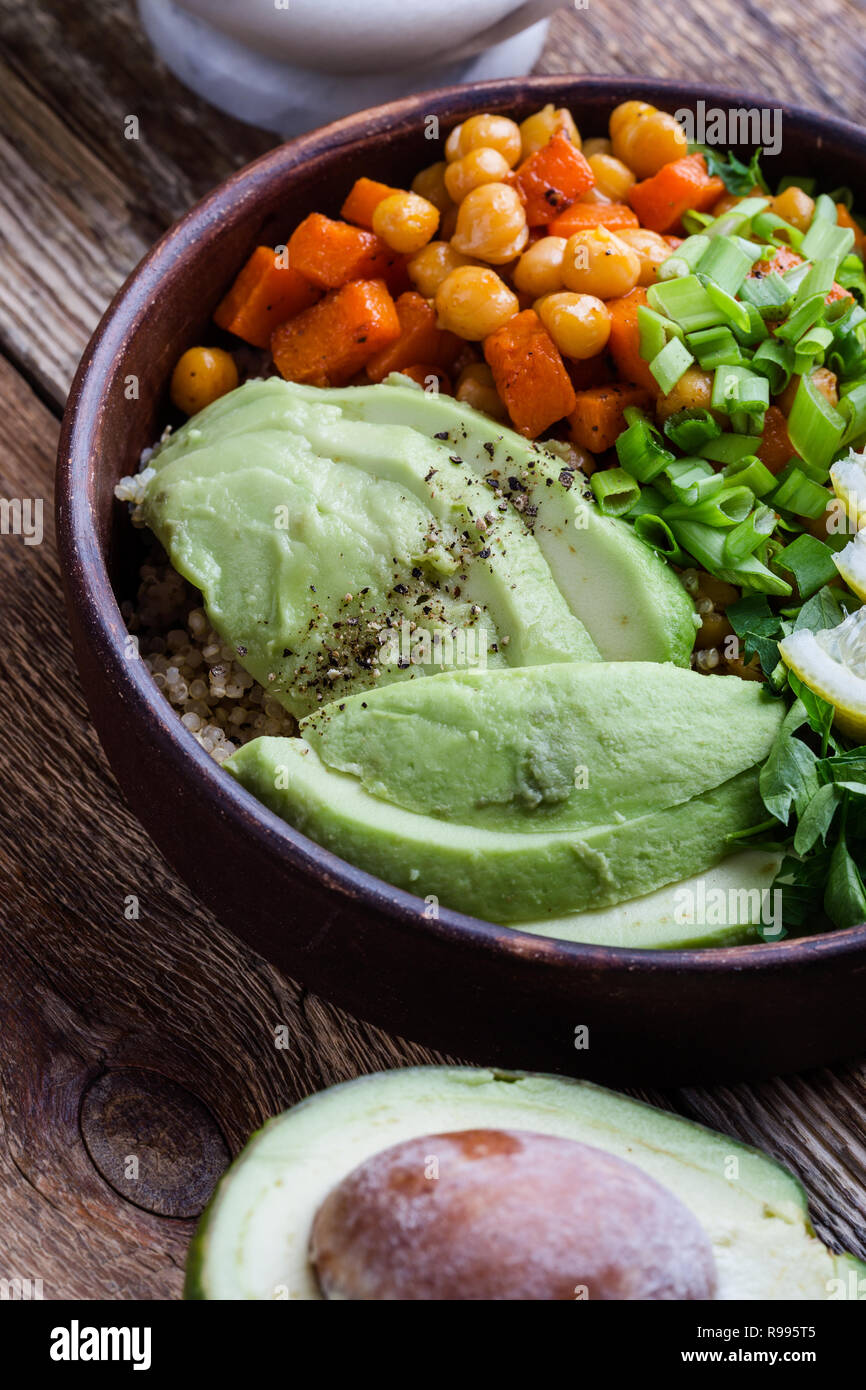Healthy chickpea avocado quinoa bowl on rustic wooden table, plant