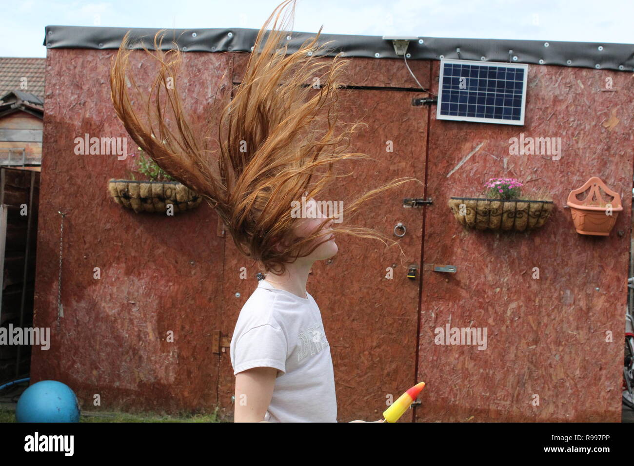 Pre-teen girl flinging her head back with long ginger hair Stock Photo