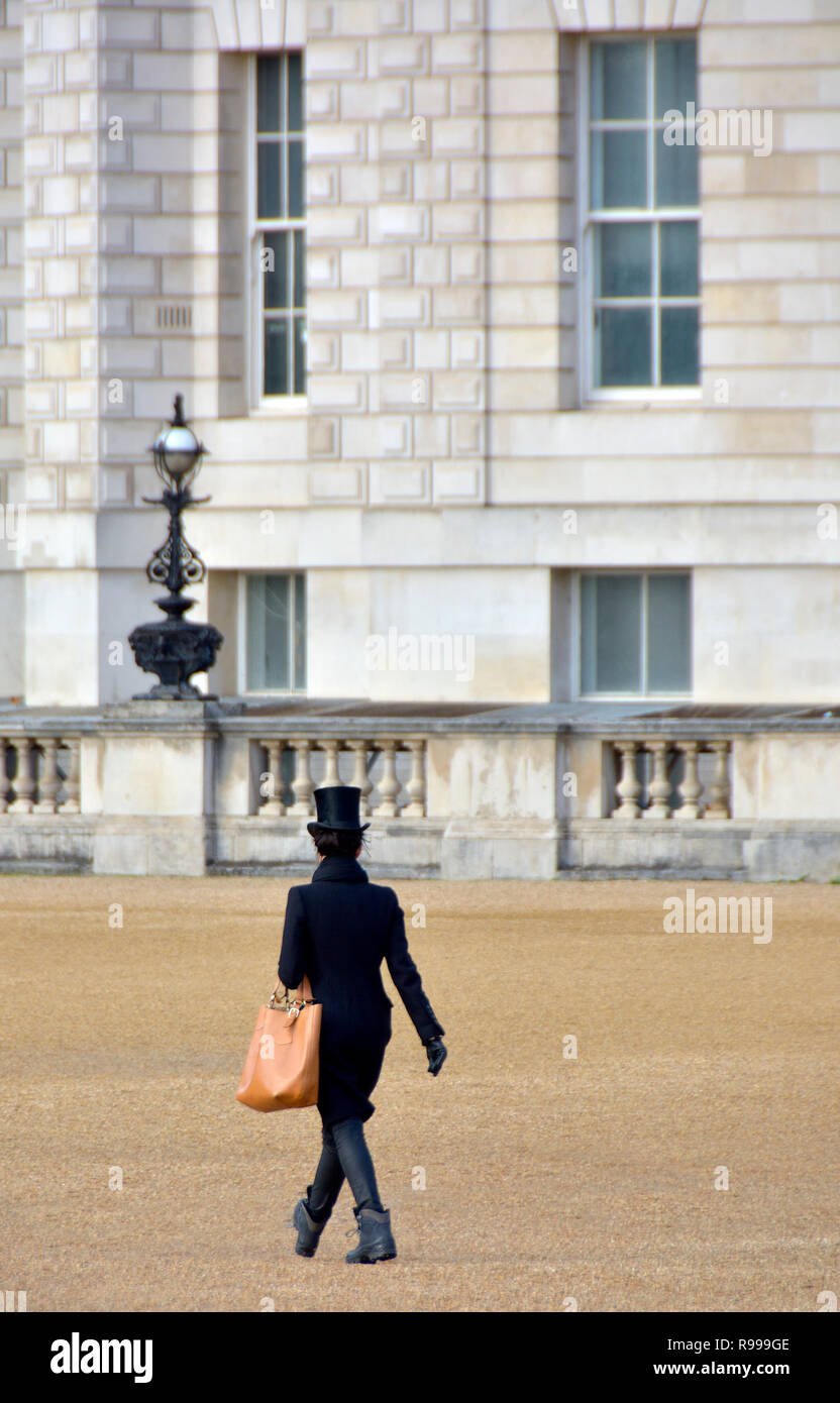London, England, UK. Stylish woman wearing a top hat walking through Horse Guards Parade, December Stock Photo