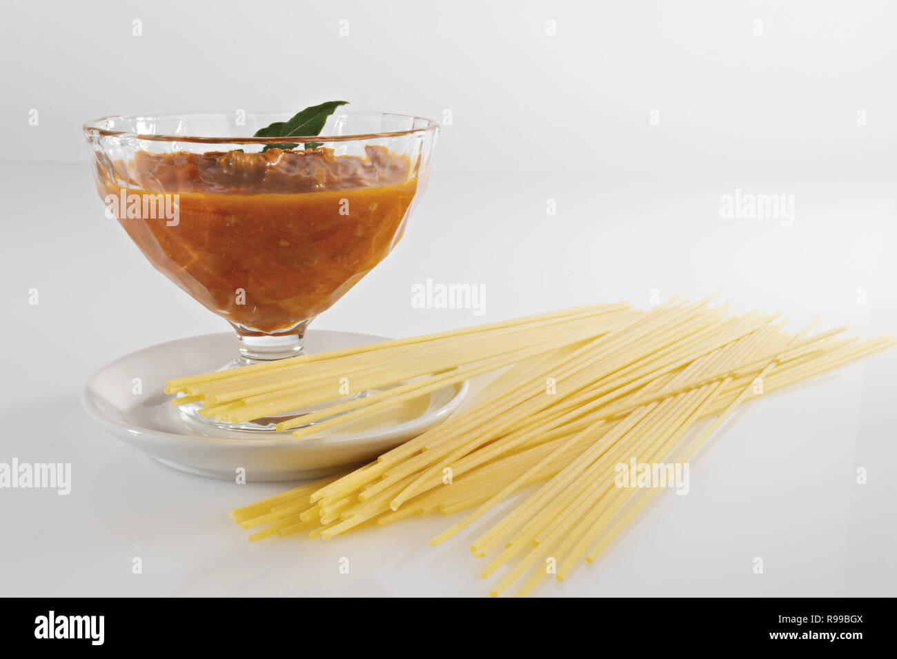 meat and tomato ragu in glass bowl and raw pasta. horizontal Stock Photo