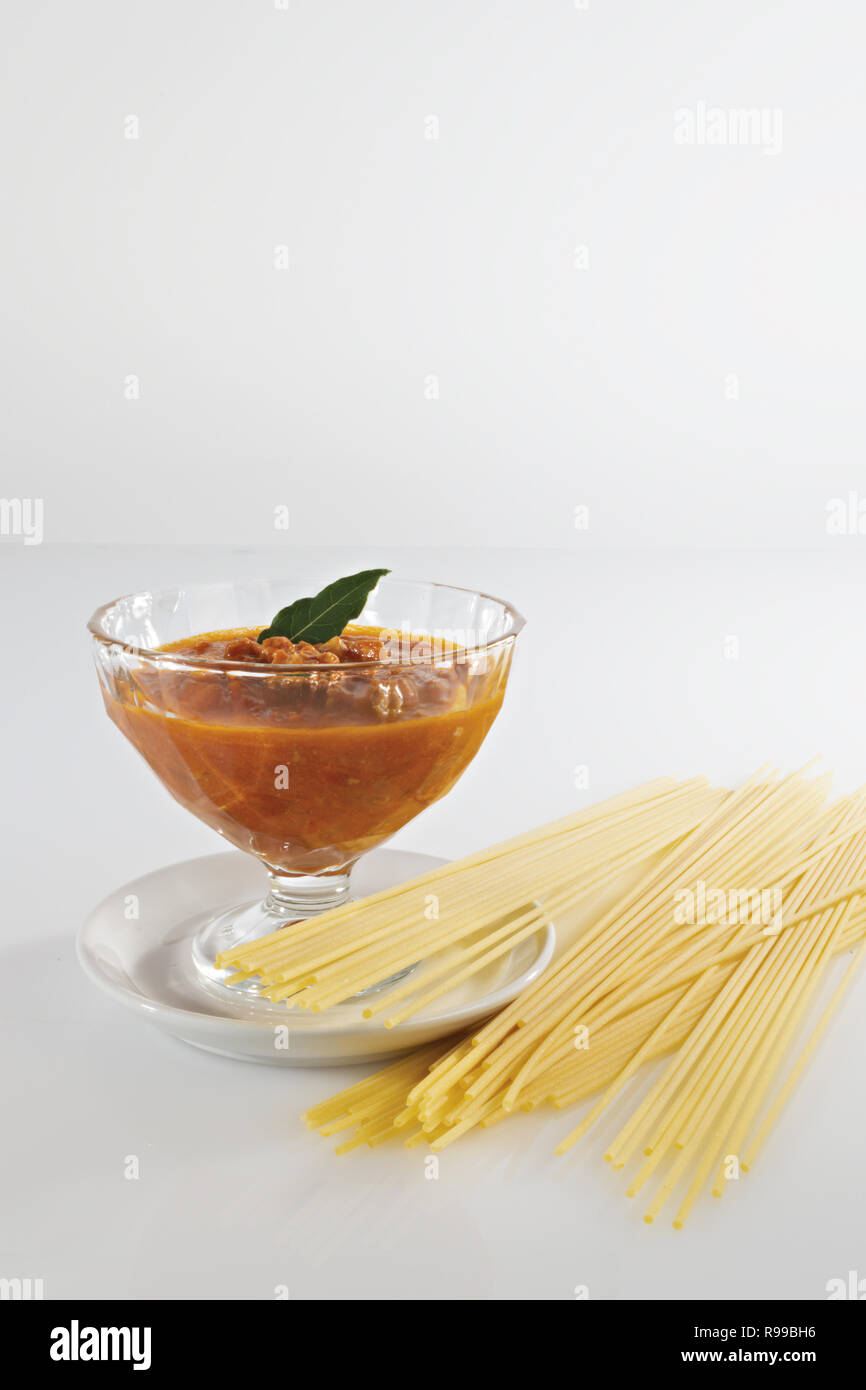 tomato in glass bowl and vertical raw pasta Stock Photo