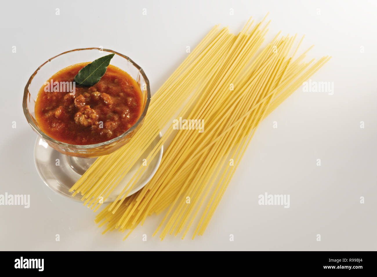 tomato in glass bowl and raw pasta horizontal from above Stock Photo