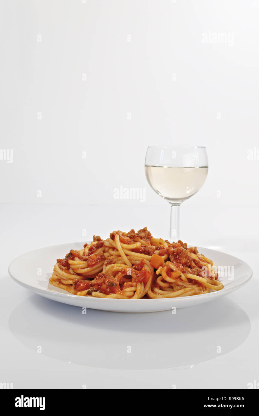 spagetti with meat and tomato ragu with vertical white wine goblet Stock Photo