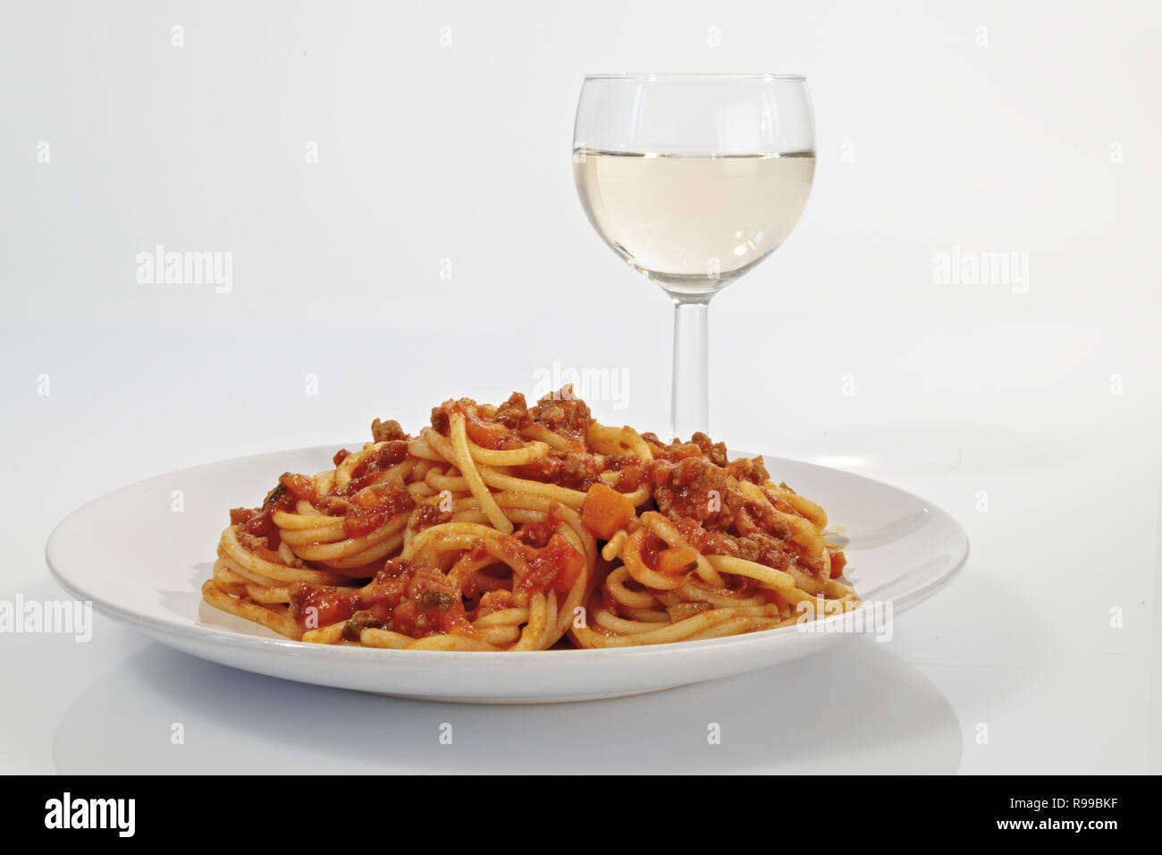 spagetti with meat and tomato ragu with a glass of white wine Stock Photo