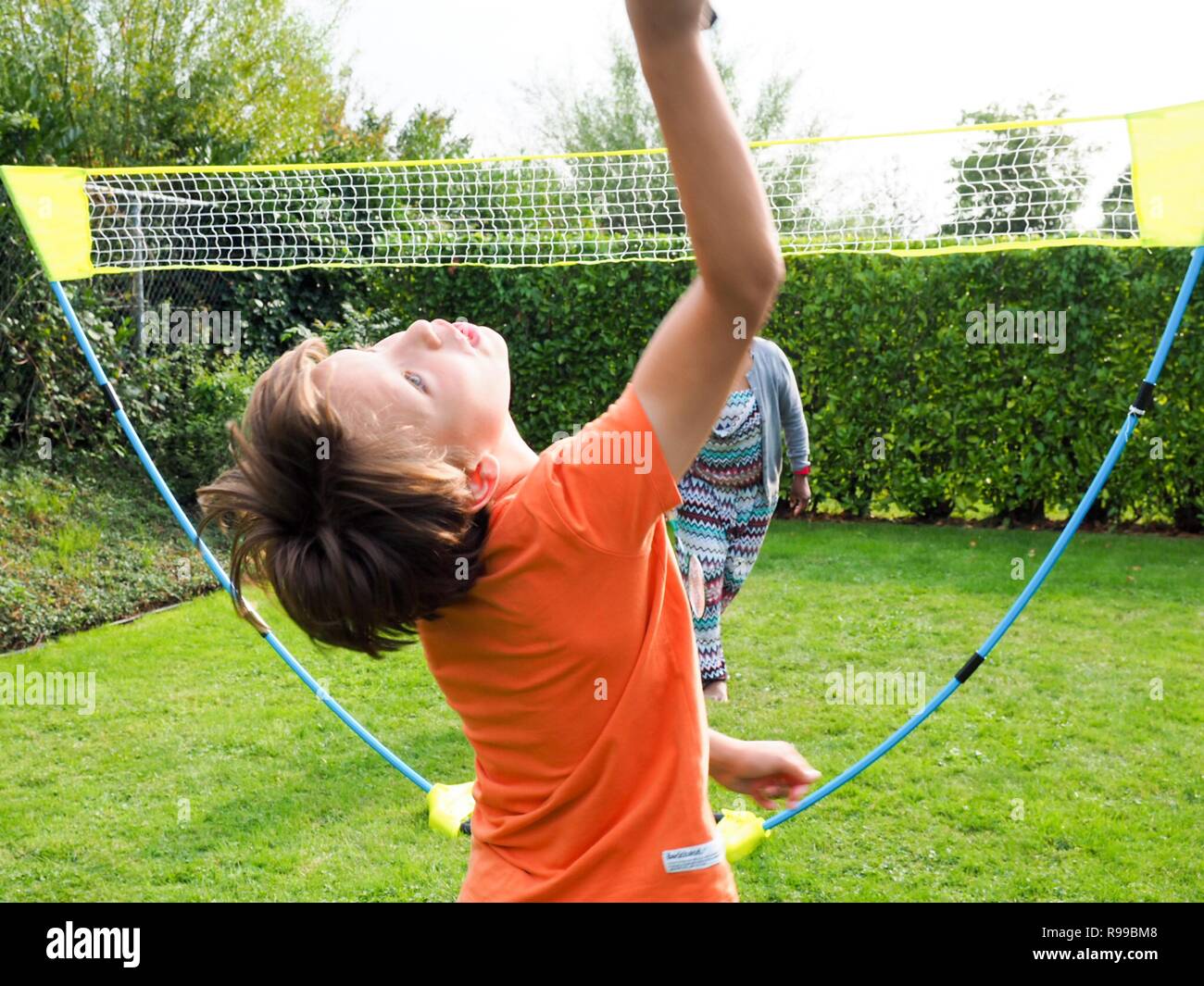Young boy leaning backwards to hit a shuttle while playing badminton Stock Photo