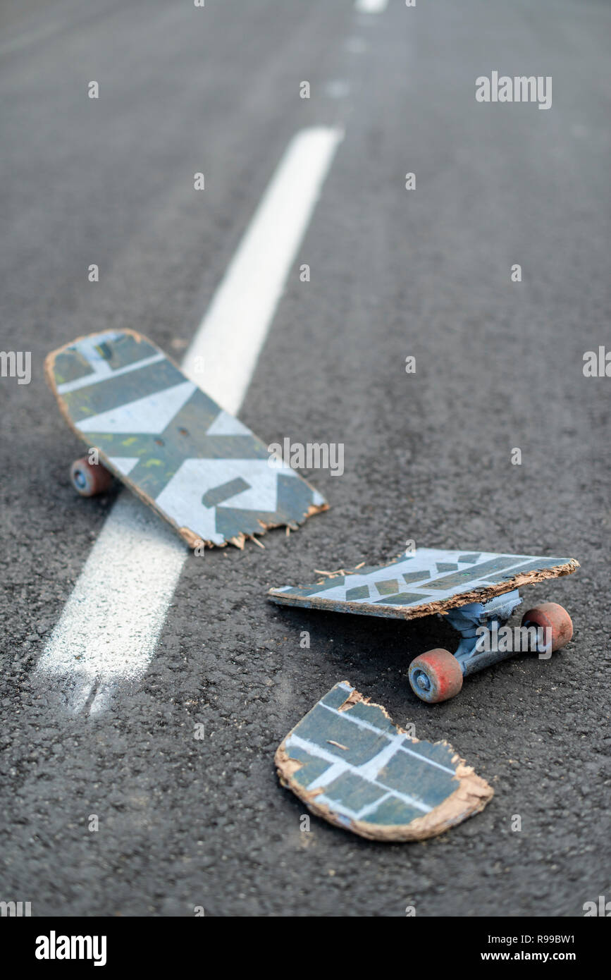 Broken skateboard on dark asphalt street. White street line Stock Photo
