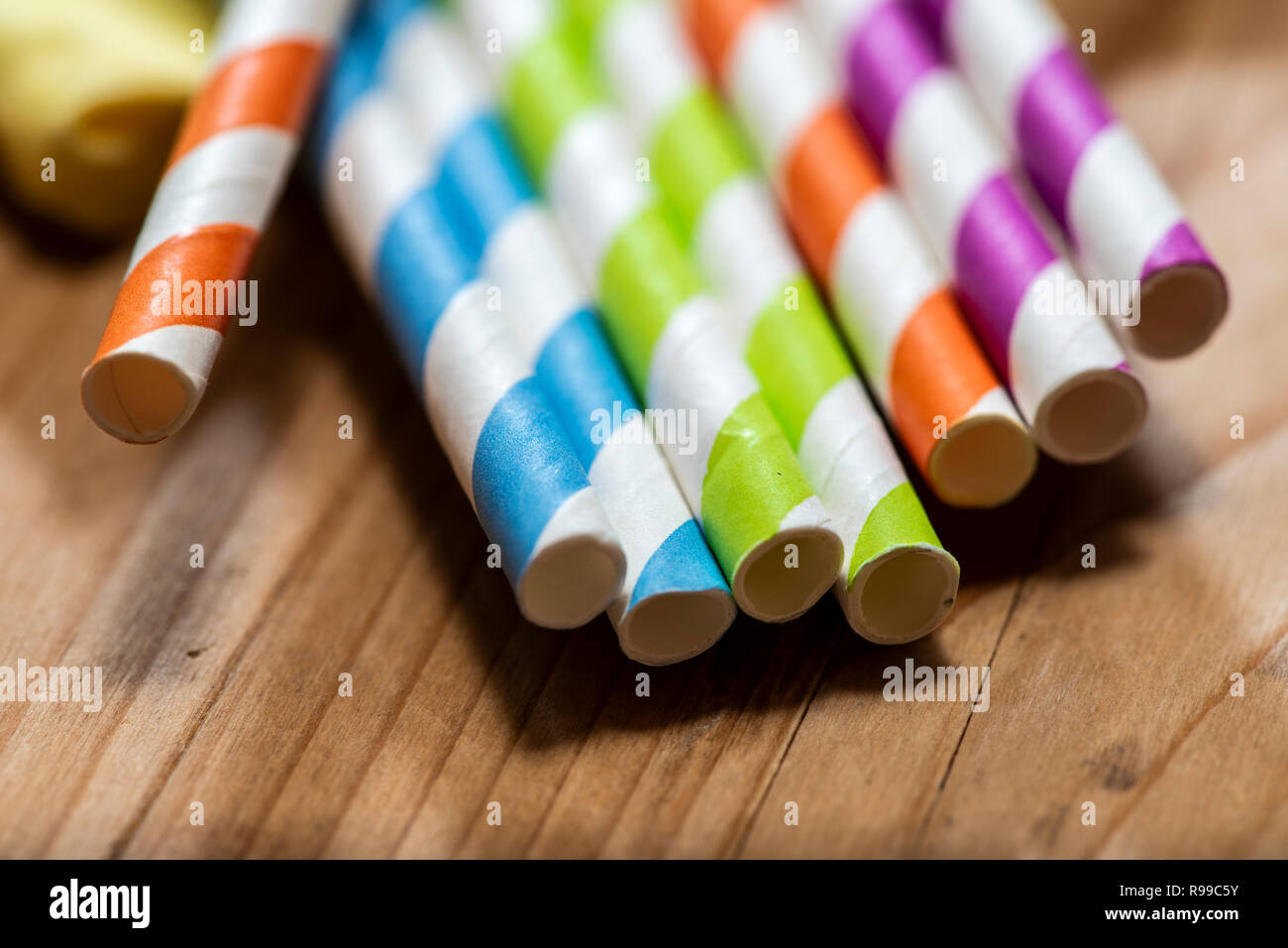 Multi Colored drinking straws placed on wooden table. Vibrant colors beverage straws made of paper. Close up macro shot. Stock Photo