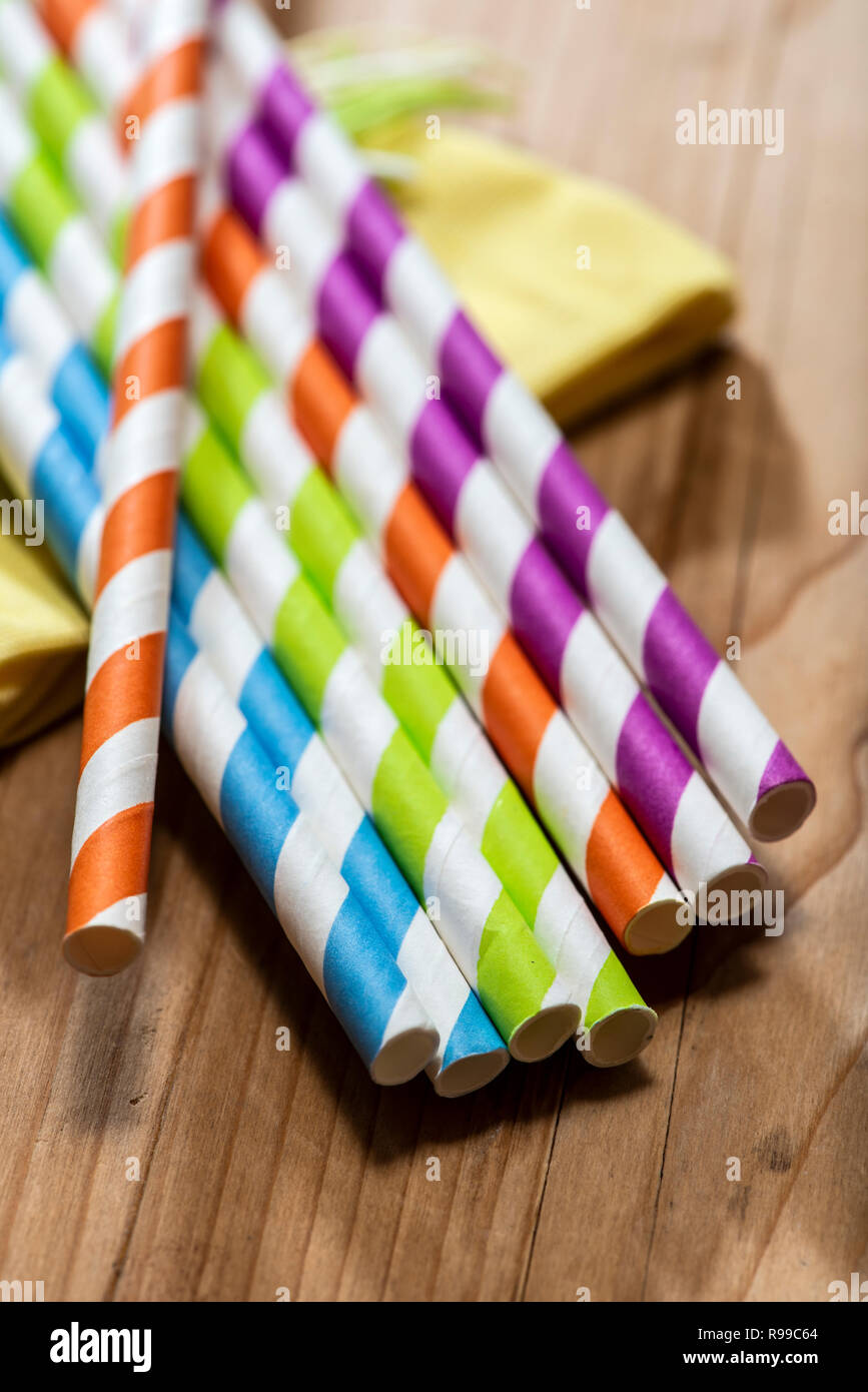 Multi Colored drinking straws placed on wooden table. Vibrant colors beverage straws made of paper. Close up macro shot. Stock Photo