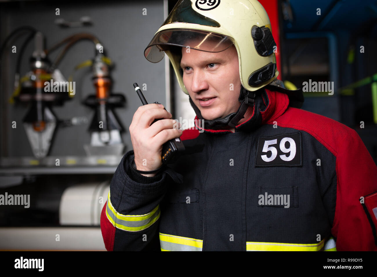 Photo of male firefighter in helmet talking on radio at fire station Stock Photo Alamy