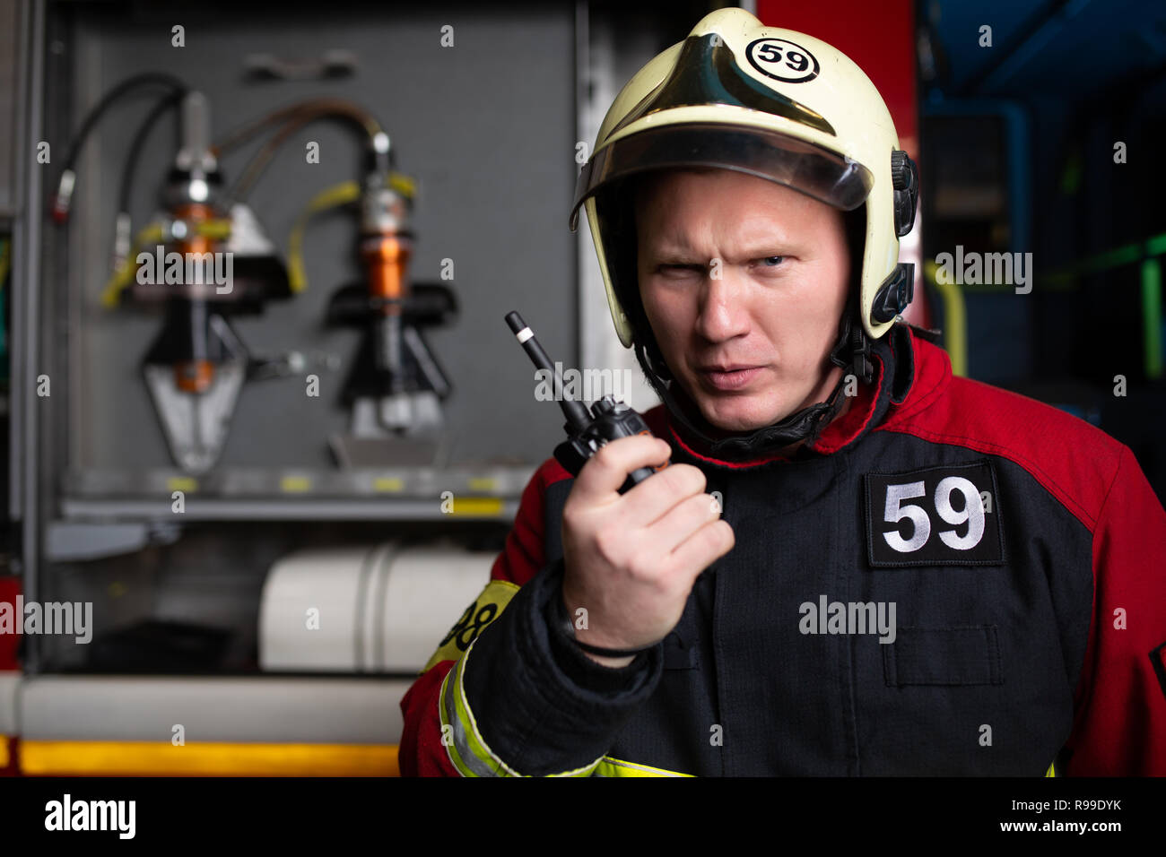 Photo of man firefighter in helmet talking on radio at fire station Stock Photo Alamy