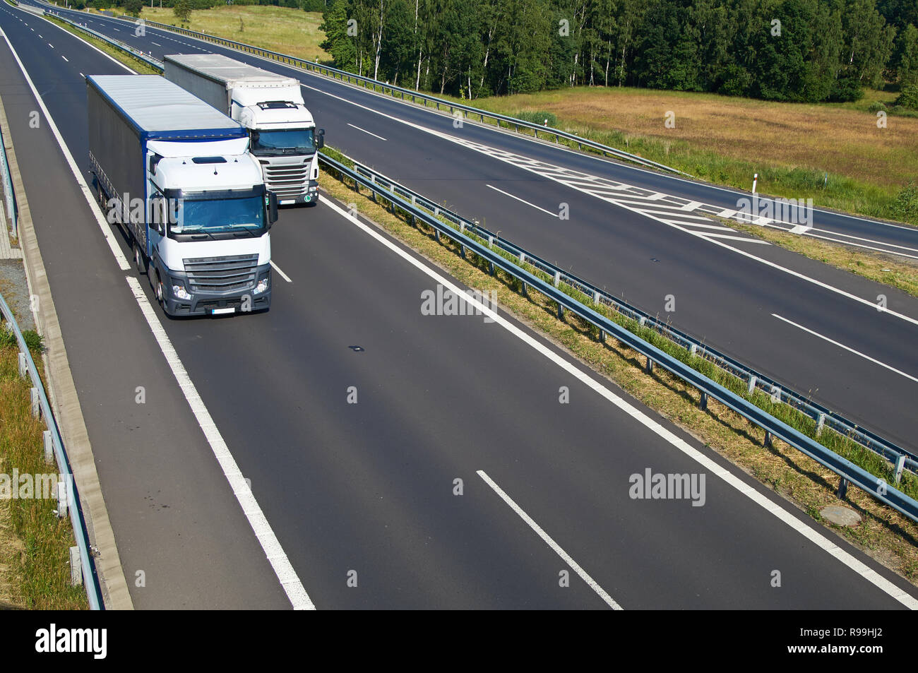 Two overtaking the white trucks on asphalt highway in the summer ...