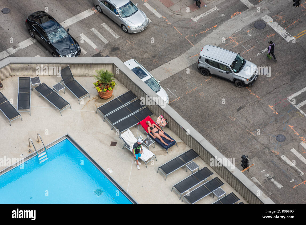 Aerial view of woman sunbathing on pool deck of highrise condo Stock Photo