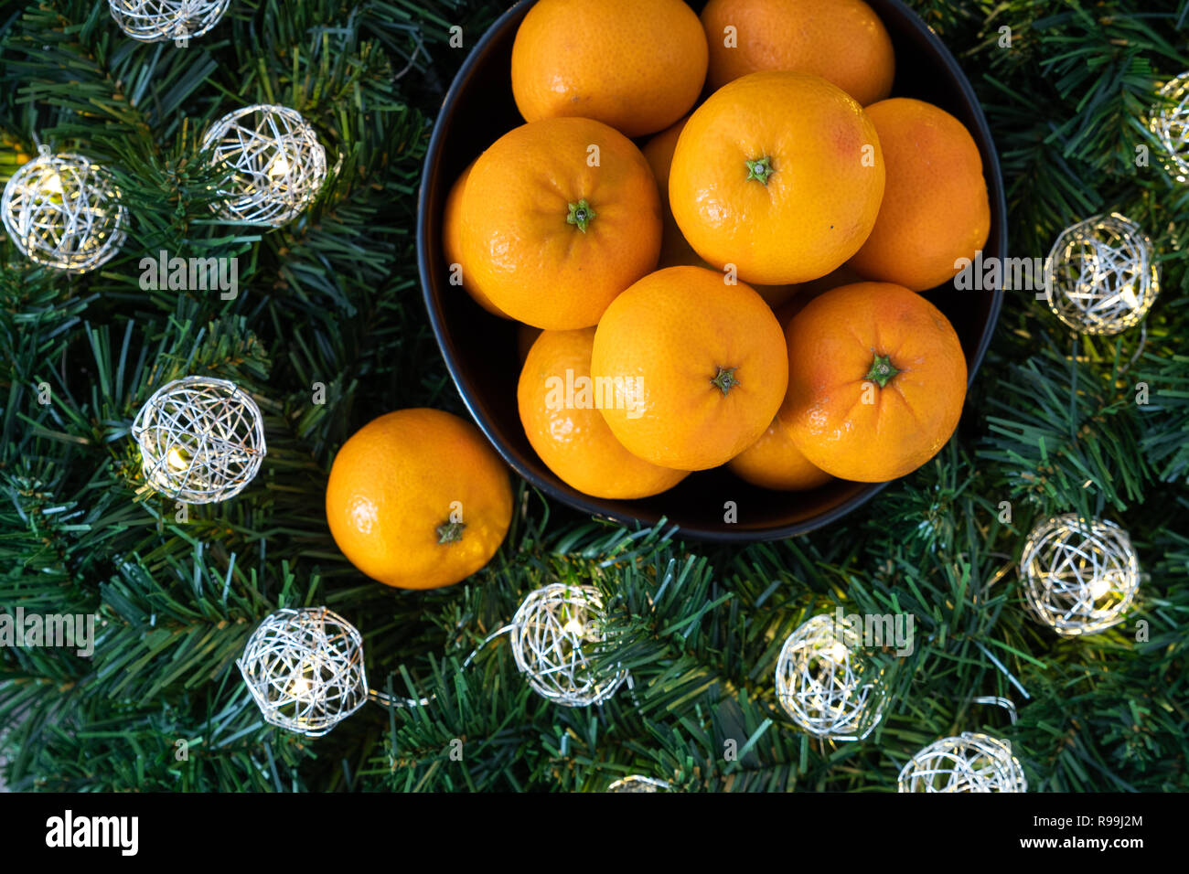 Bunch of satsuma oranges in a black bowl, in a wreath with LED