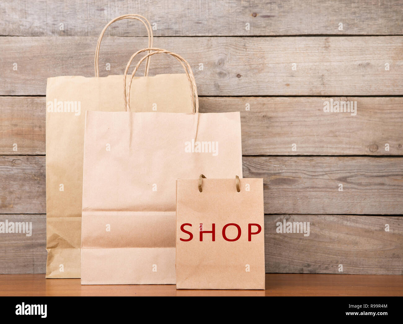 Shopping bags with inscription 'SHOP' on wooden background Stock Photo