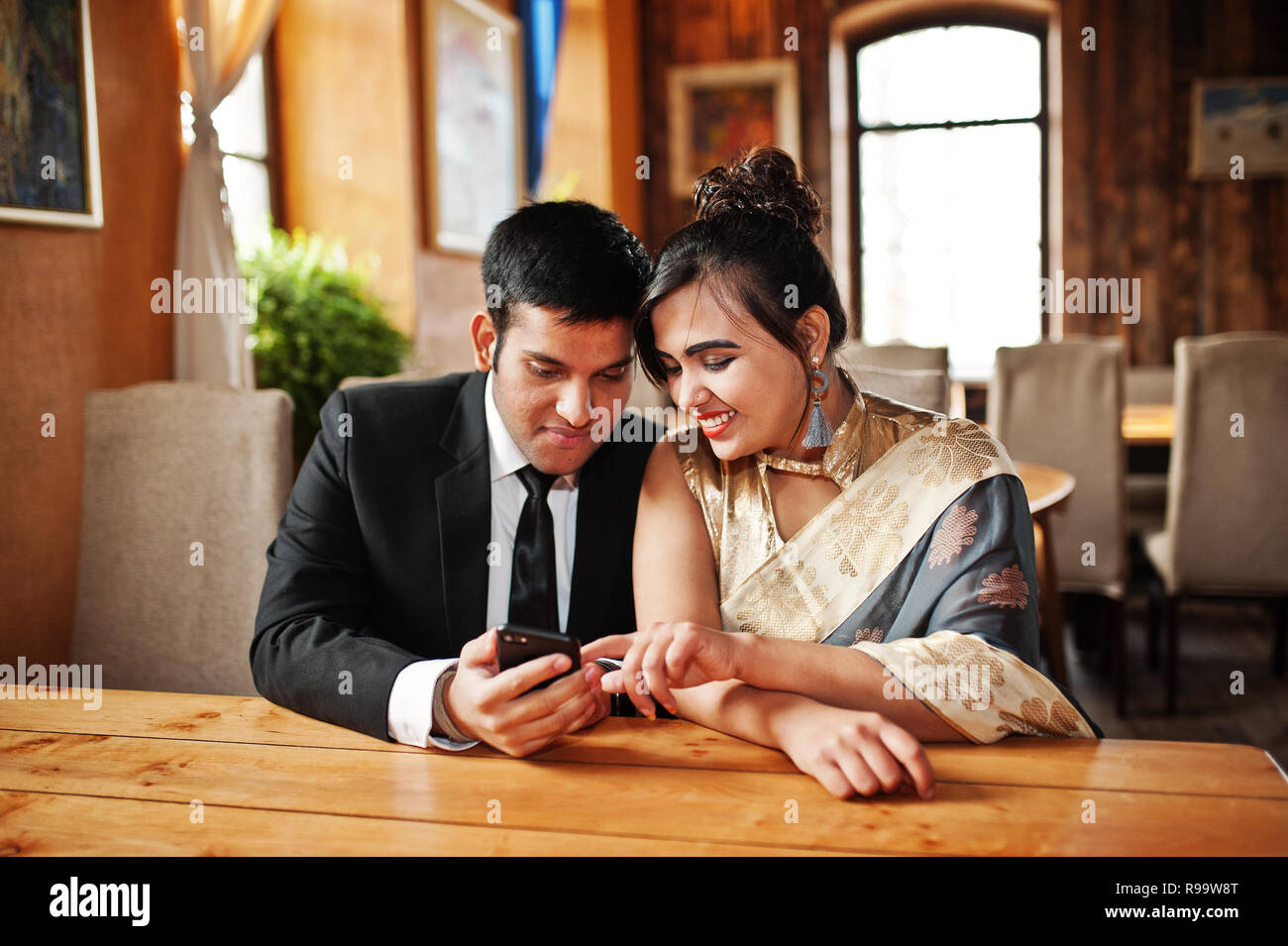 Free Photo | Lovely indian couple in love wear at saree and elegant suit  posed on restaurant back of them they looking on window and holds hands