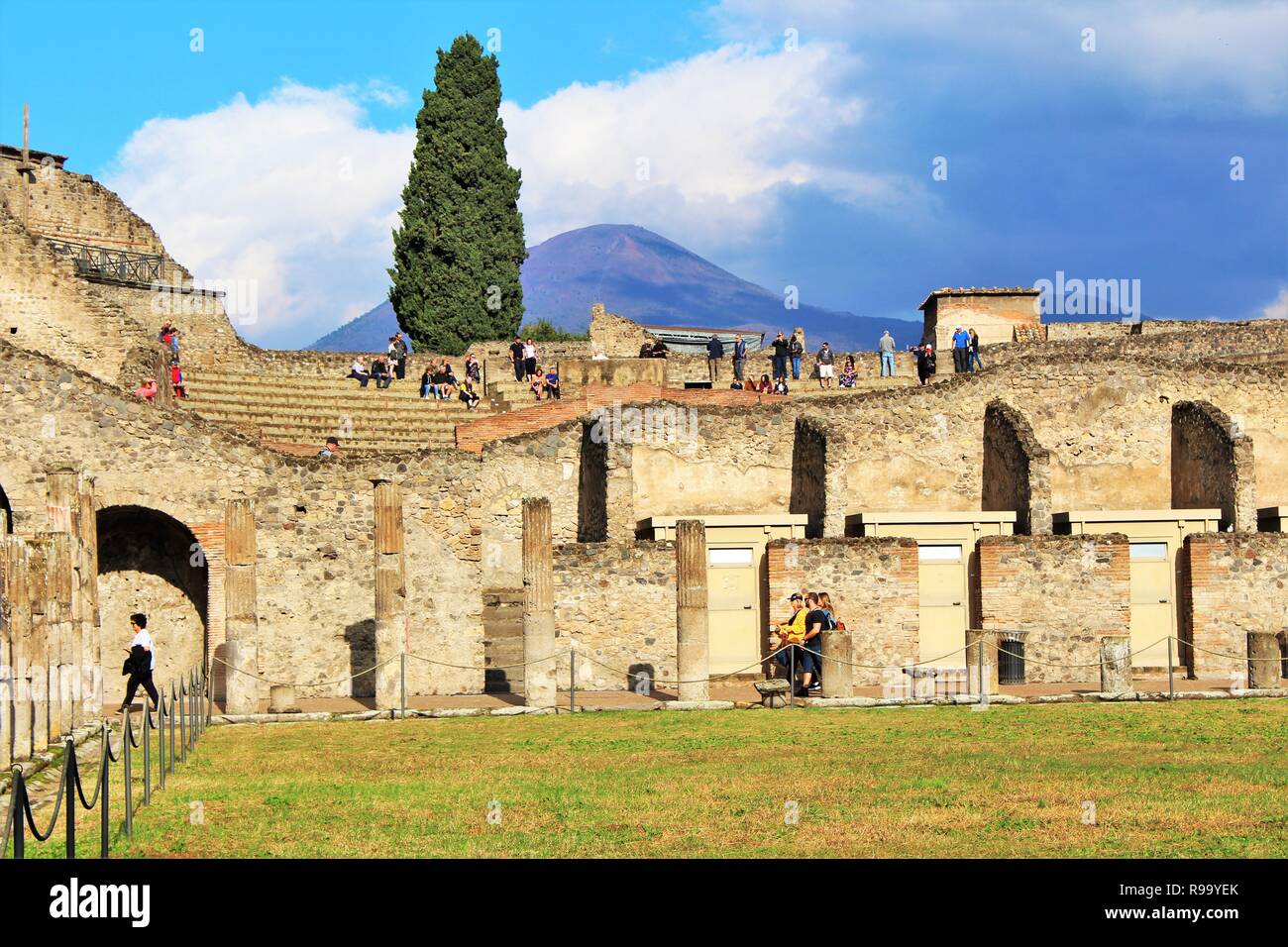 Pompeii, Italy - October 23rd 2018: Tourists explore the ruins of the amphitheater in the ancient city of Pompeii, with Mount Vesuvius in the distance Stock Photo