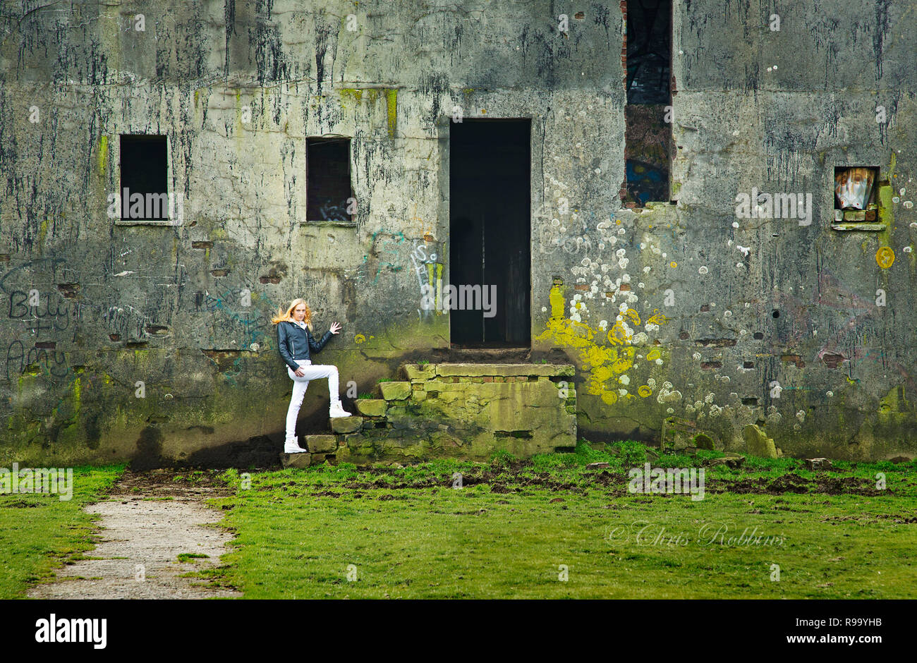 A young blond model entering an old disused building Stock Photo