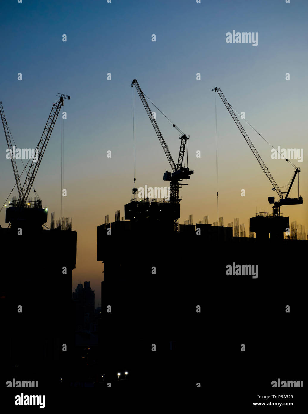 Silhouette of tower cranes at construction site Stock Photo - Alamy