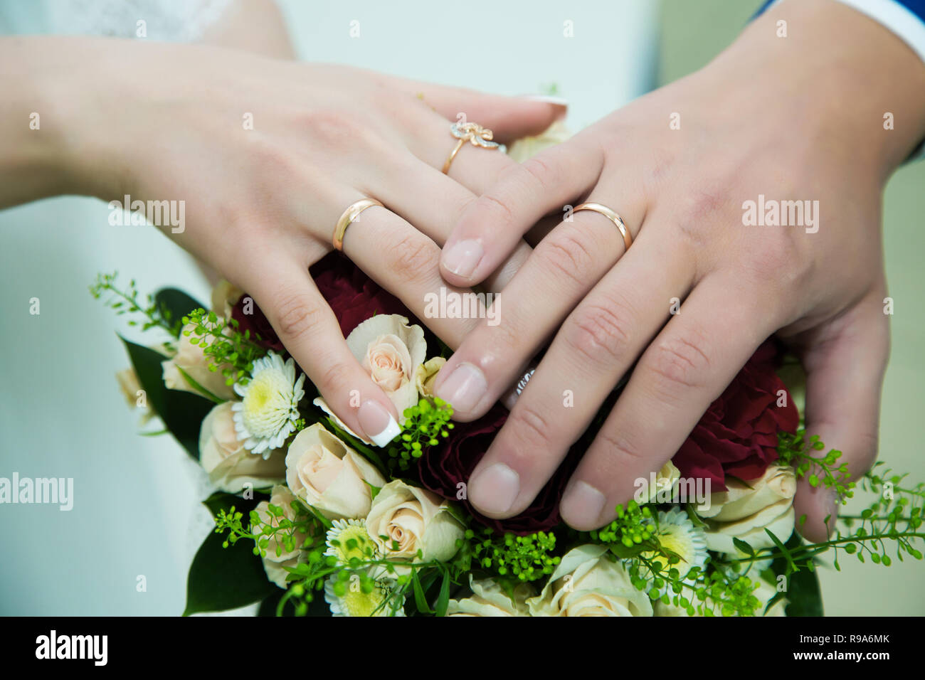 hands of the bride and groom with wedding rings on the wedding bouquet ...
