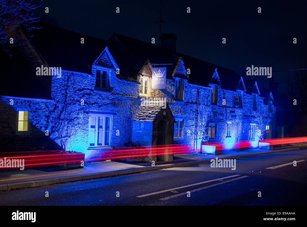The Crown of Crucis country inn and hotel at lit by blue lights night. Ampney Crucis, Cotswolds, Cirencester, Gloucestershire, England Stock Photo