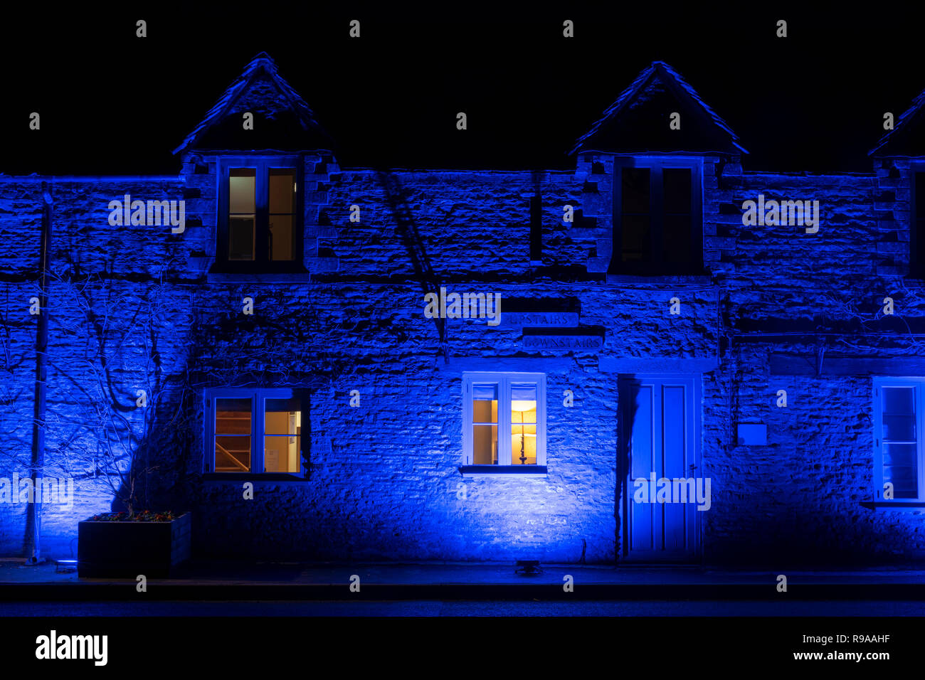 The Crown of Crucis country inn and hotel at lit by blue lights night. Ampney Crucis, Cotswolds, Cirencester, Gloucestershire, England Stock Photo
