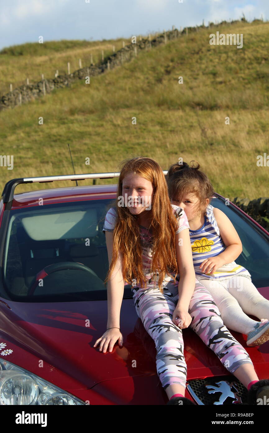 two children sitting on a Peugeot 308 red car Stock Photo