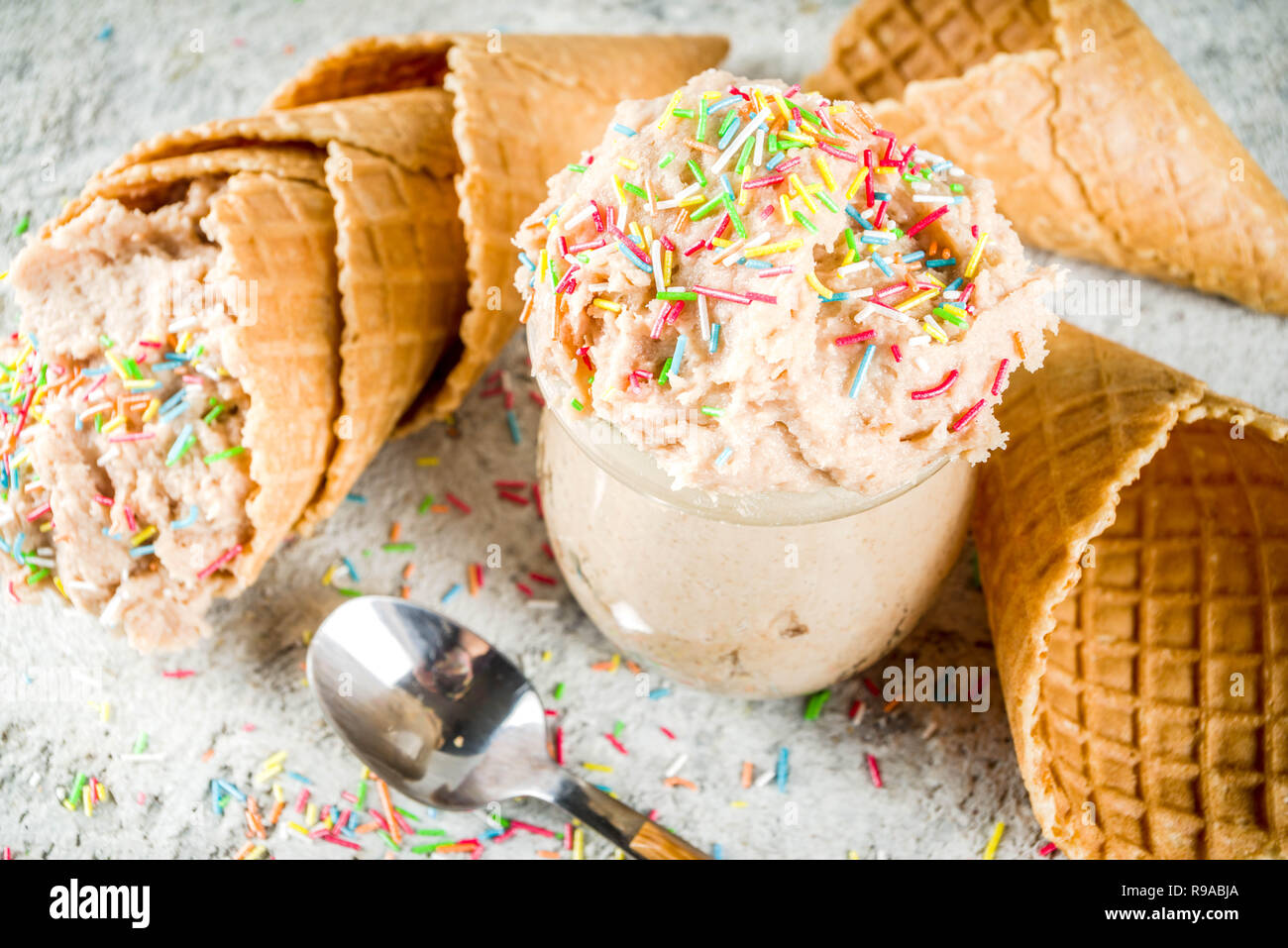 Edible Raw Cookie Dough, sweet modern dessert, with waffle ice cream cones on grey stone background, copy space Stock Photo