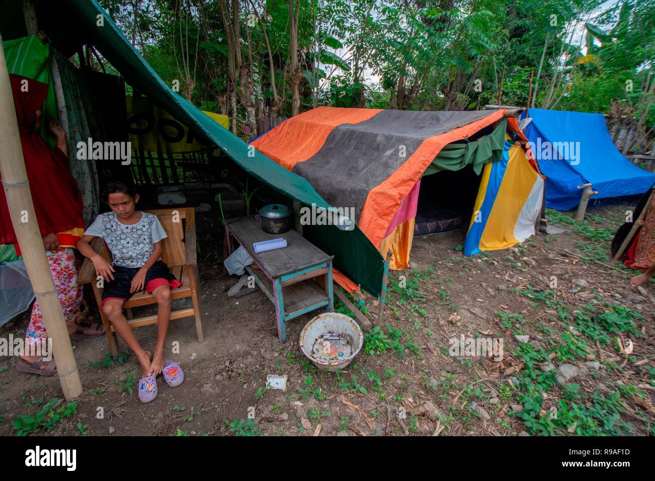 Palu, Indonesia, December 21, 2018: Residents affected by the disaster move under tents in the refugee camp of Toaya Vunta Village, Donggala, Central Sulawesi, Indonesia, Friday (December 21, 2018). After entering a period of recovery, refugees with a total of 120 heads of household in the area began to lack food due to the reduction in aid and in the meantime, refugees had lost their jobs due to the earthquake and tsunami that hit their settlements on 28 September 2018. Stock Photo