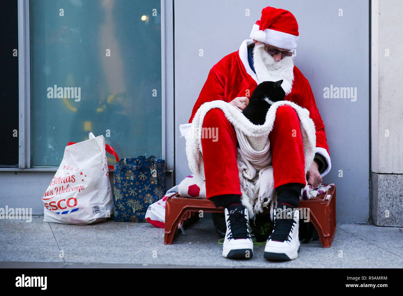 London, UK, 21st December 2018. A homeless man dressed as Santa Claus is seen seated on London's Oxford Street. On 18 December, Gyula Remes from Hungary died after choking on his own vomit outside the Houses of Parliament. According to official statistics published by the Office for National Statistics, 597 homeless people died in England and Wales in 2017. Credit: SOPA Images Limited/Alamy Live News Stock Photo