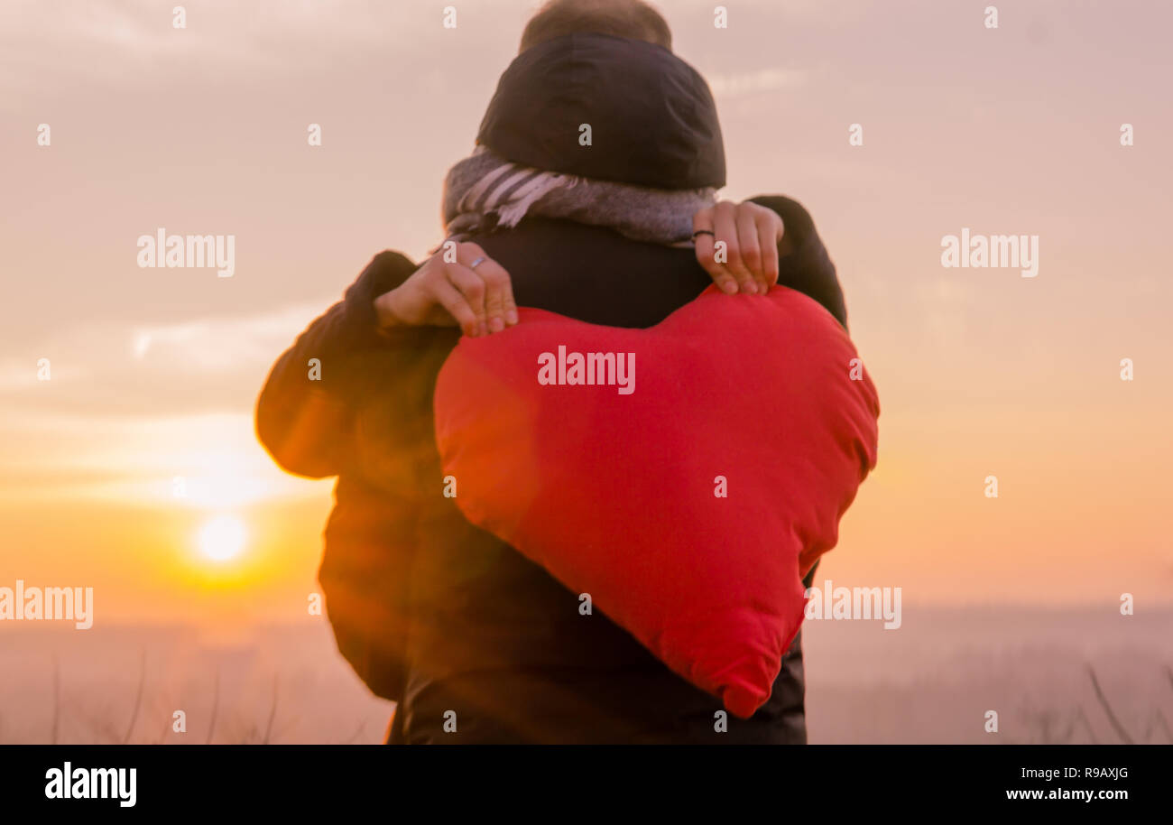 Portrait of young romantic couple in love whit red heart at sunset moment. Stock Photo