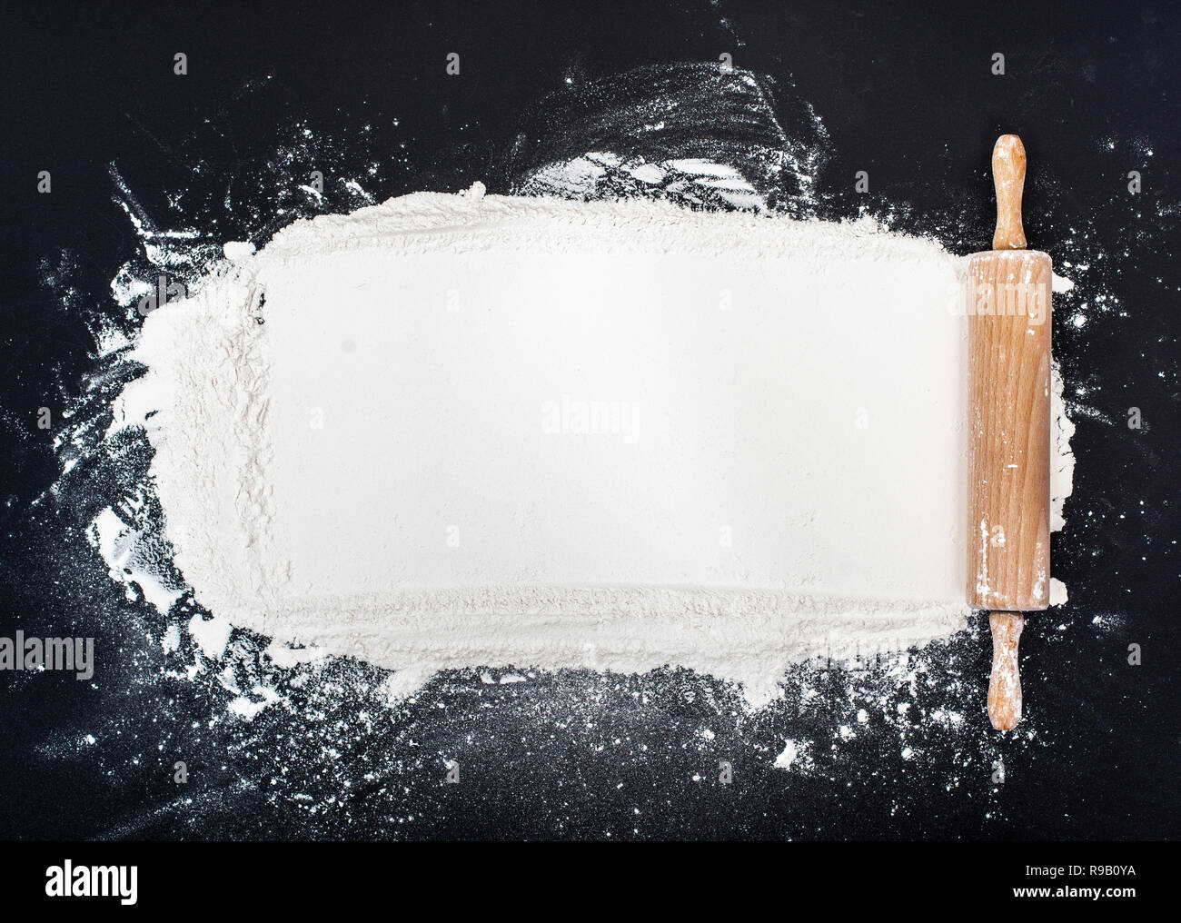 Baking background with rolling pin and flour on black background Stock