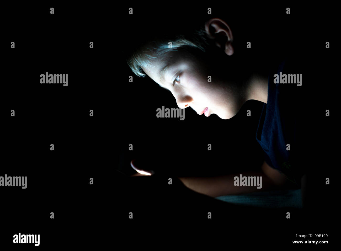 young boy on smartphone at night alone in the dark Stock Photo