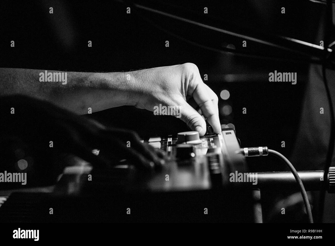 Musician playing keyboards and adjusting settlings knob Stock Photo