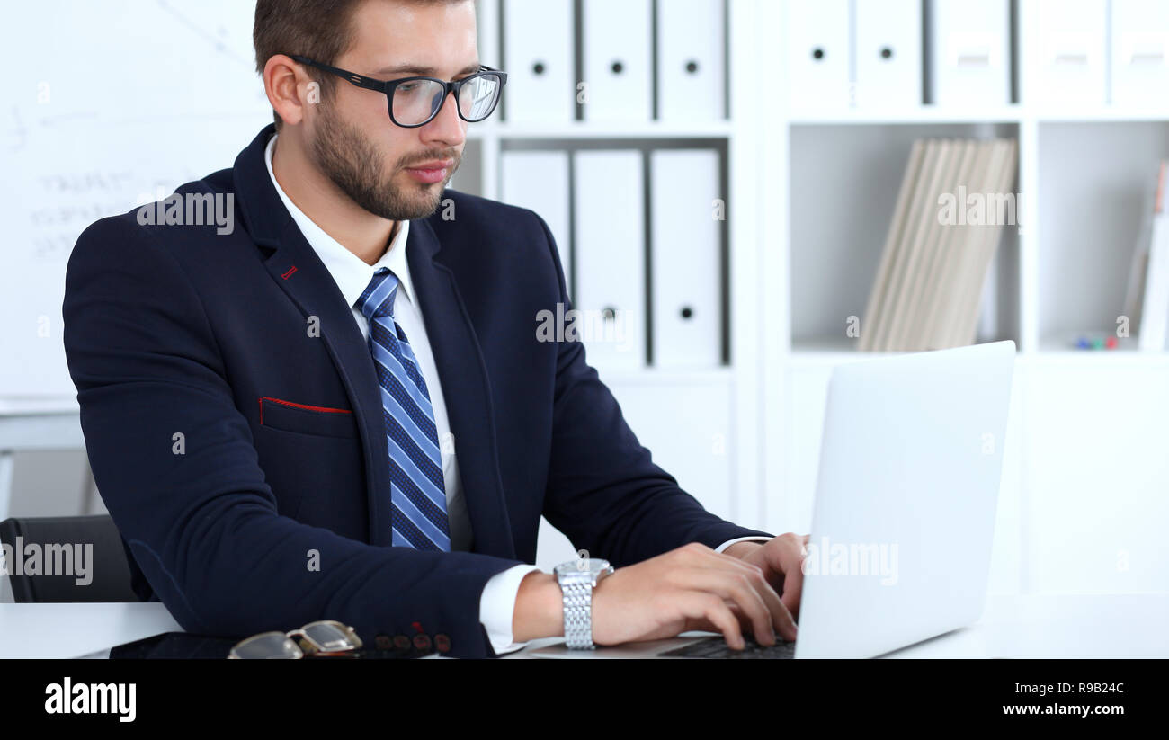 Businessman using laptop computer while sitting at the desk in office ...
