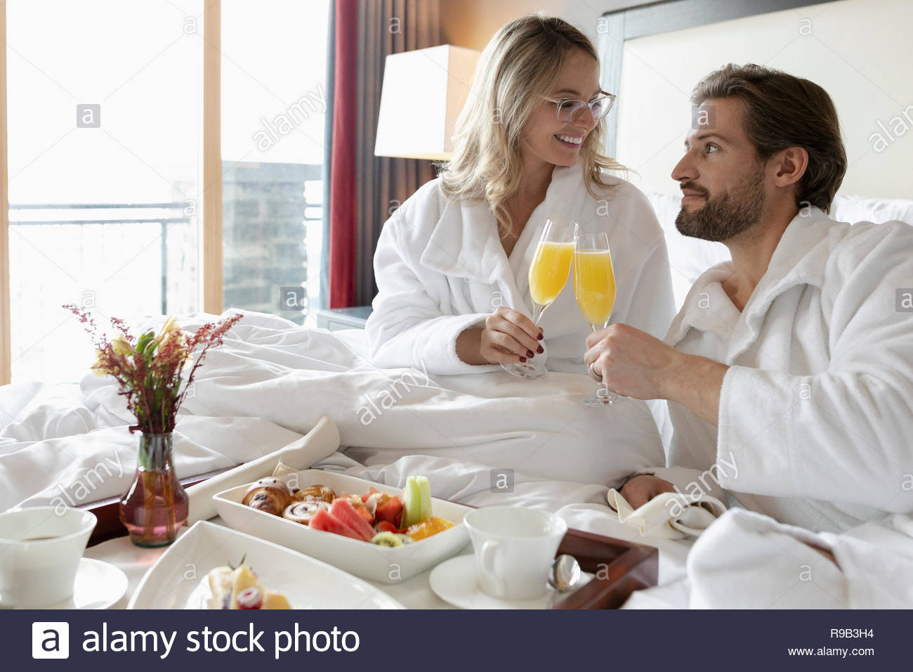 Couple in bathrobes drinking mimosas in hotel room, enjoying romantic weekend Stock Photo Alamy