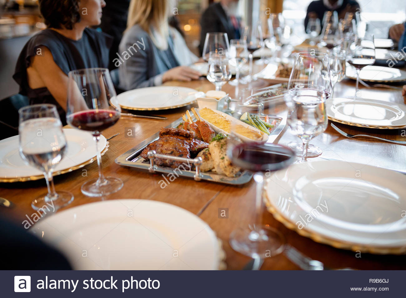 People dining, enjoying red wine at long restaurant table Stock Photo ...