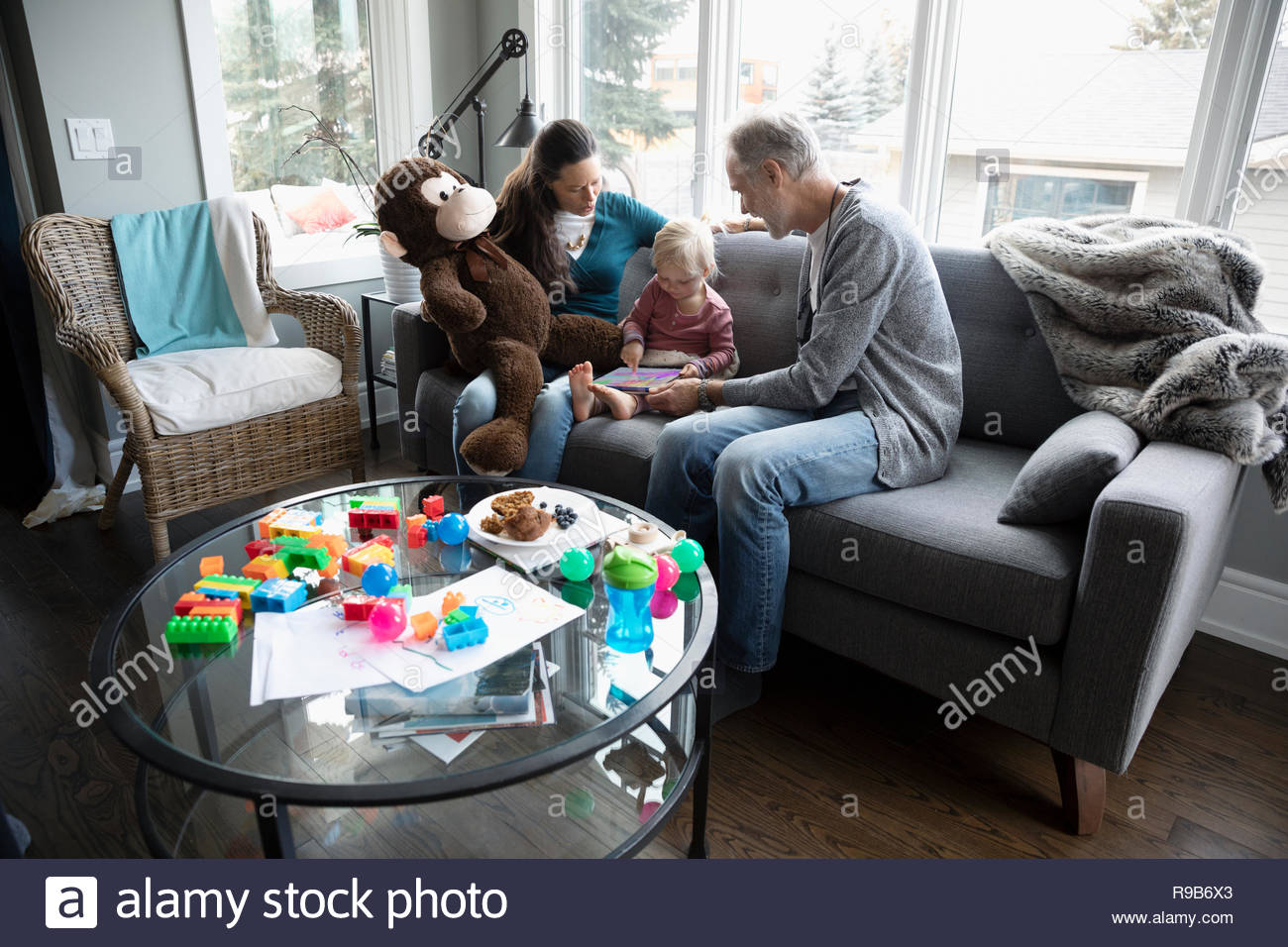 Grandparents and toddler granddaughter using digital tablet on living room sofa Stock Photo