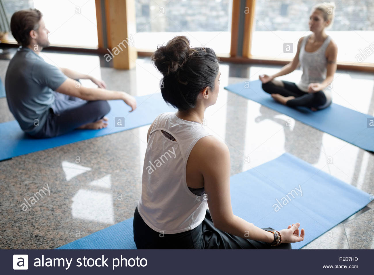 Serene people practicing yoga, sitting in lotus position in studio Stock Photo