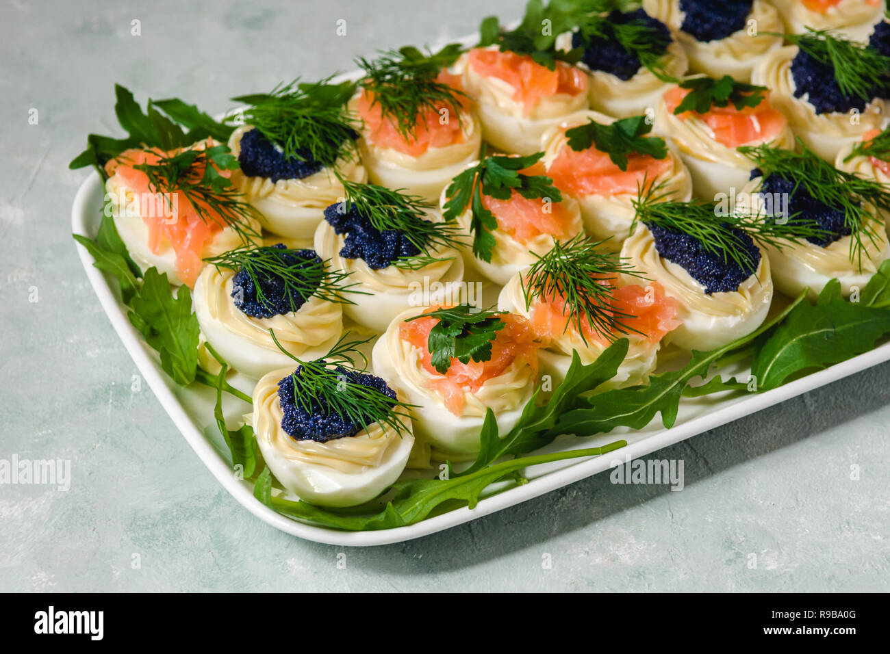 Stuffed eggs with salmon and caviar decorated by parsley and dill