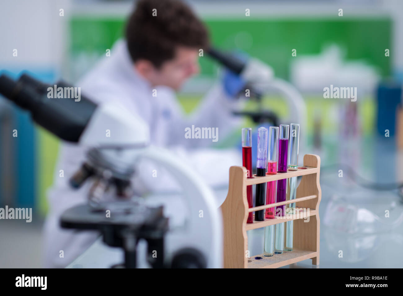 Young student scientist looking through a microscope while doing some research in the laboratory Stock Photo