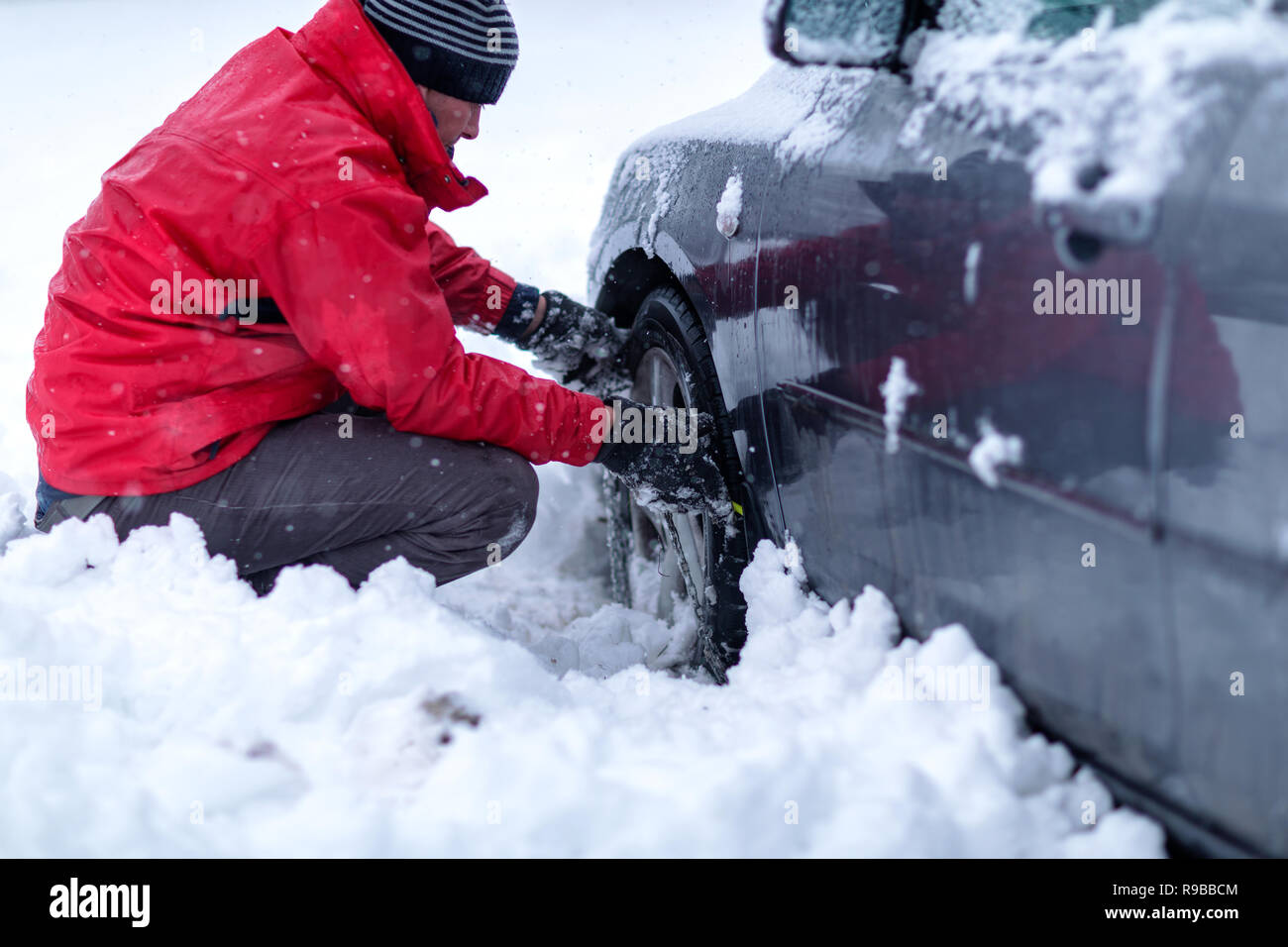 Clutching the snow chains. Snow chains on the wheels of car. young man