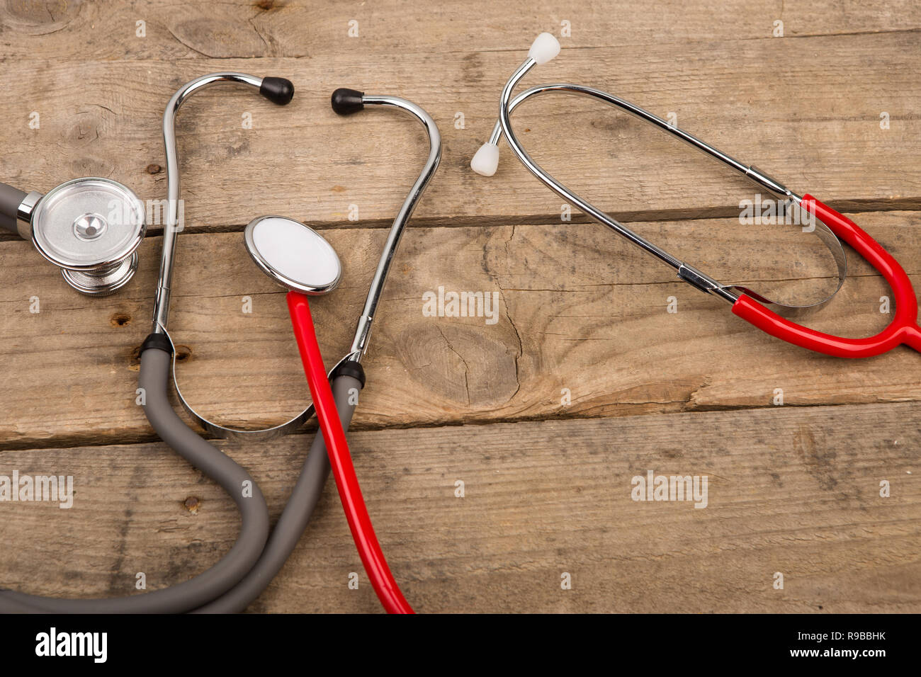 Grey and red stethoscopes on wooden desk Stock Photo