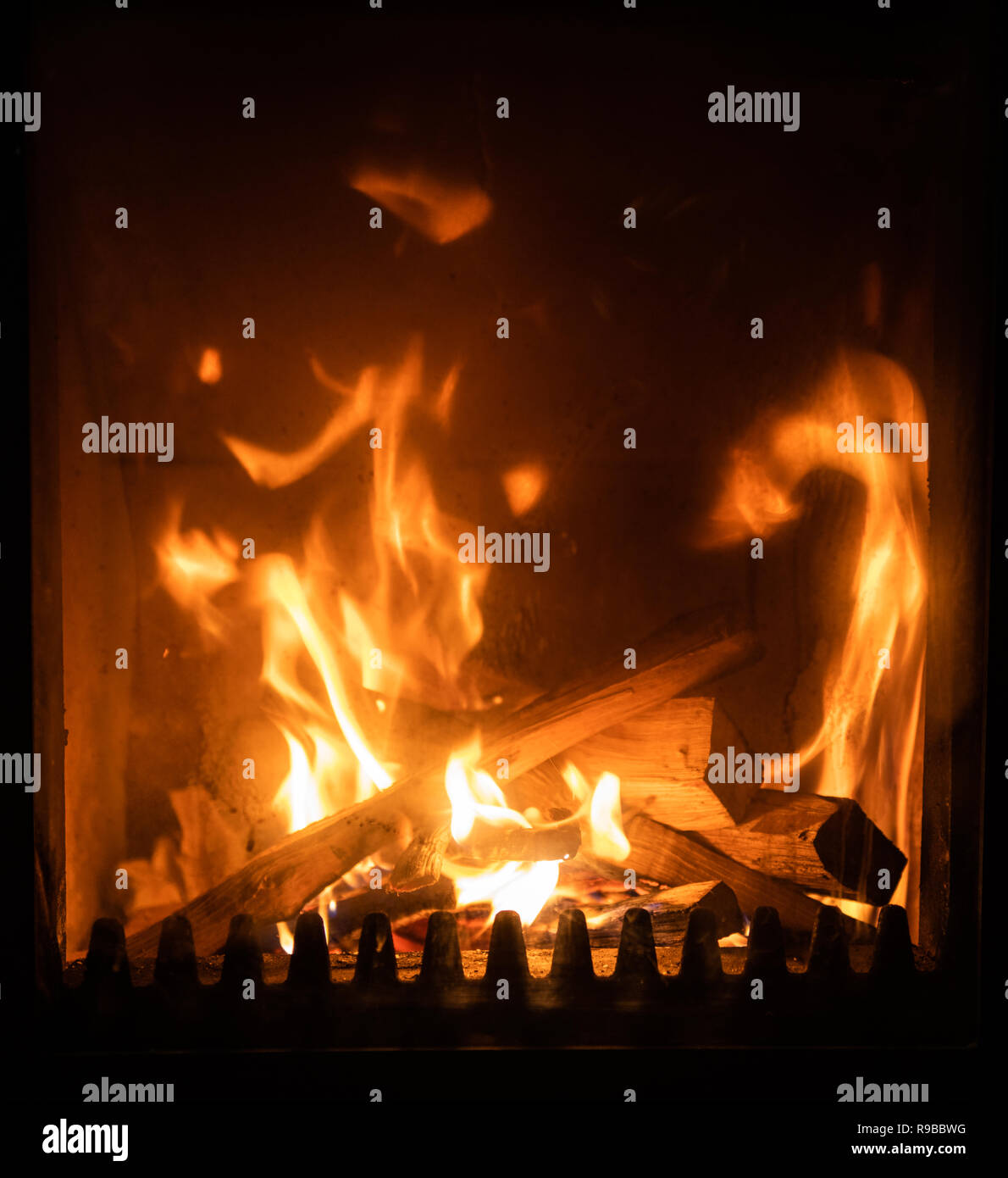 Firewood burning in stove, logs engulfed in flames, detail interior
