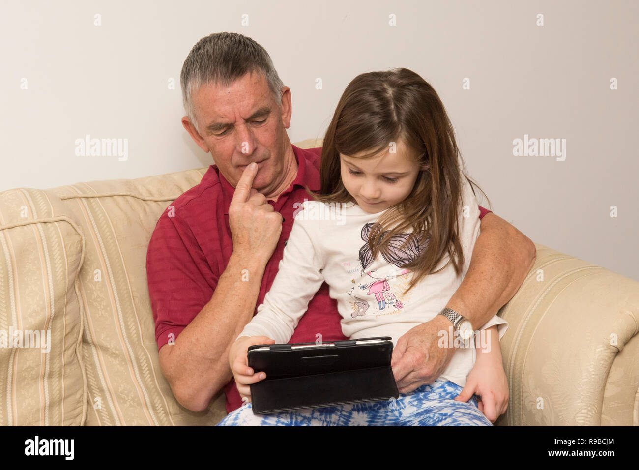 granddaughter  helping grandfather with tablet, electronic device, social media, modern technology. girl helping ageing father with iPad, tablet. Stock Photo