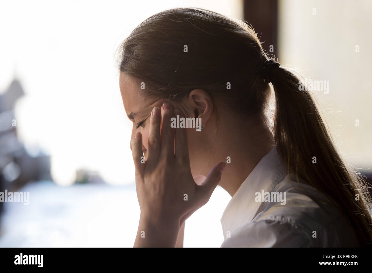 Strong headache concept, young exhausted woman feeling pain touc Stock Photo