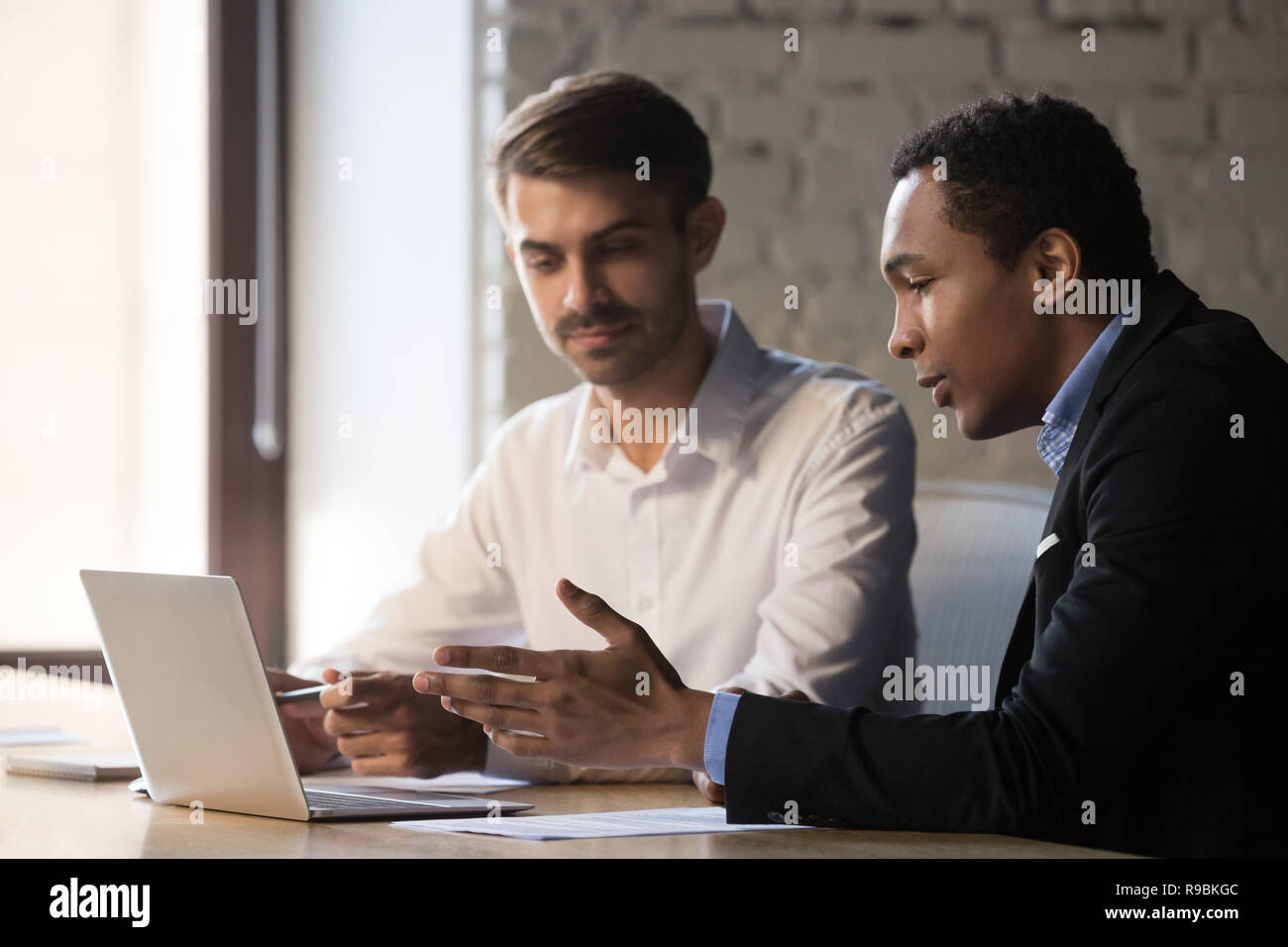 African manager consulting caucasian client showing online prese Stock Photo